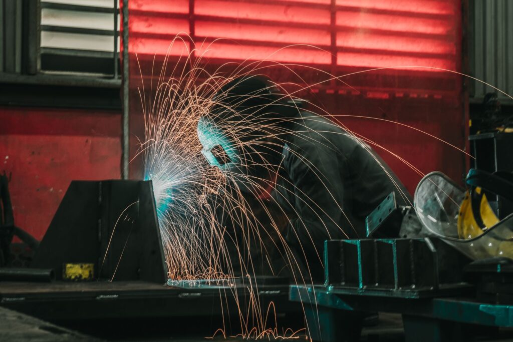 Welder in a protective helmet welding steel in a workshop, with sparks flying