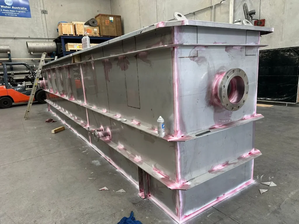 Stainless steel tank with red dye penetrant applied along the welds for crack detection