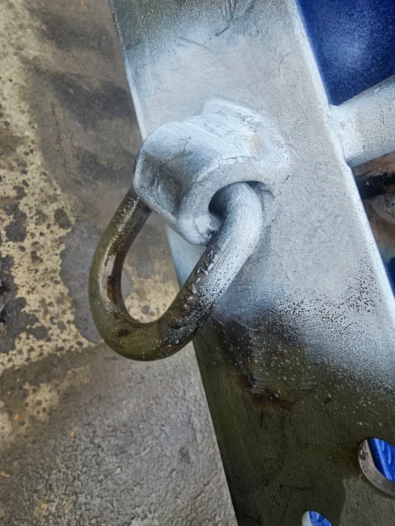 Close-up of a welded lifting lug on a galvanised steel structure being inspected